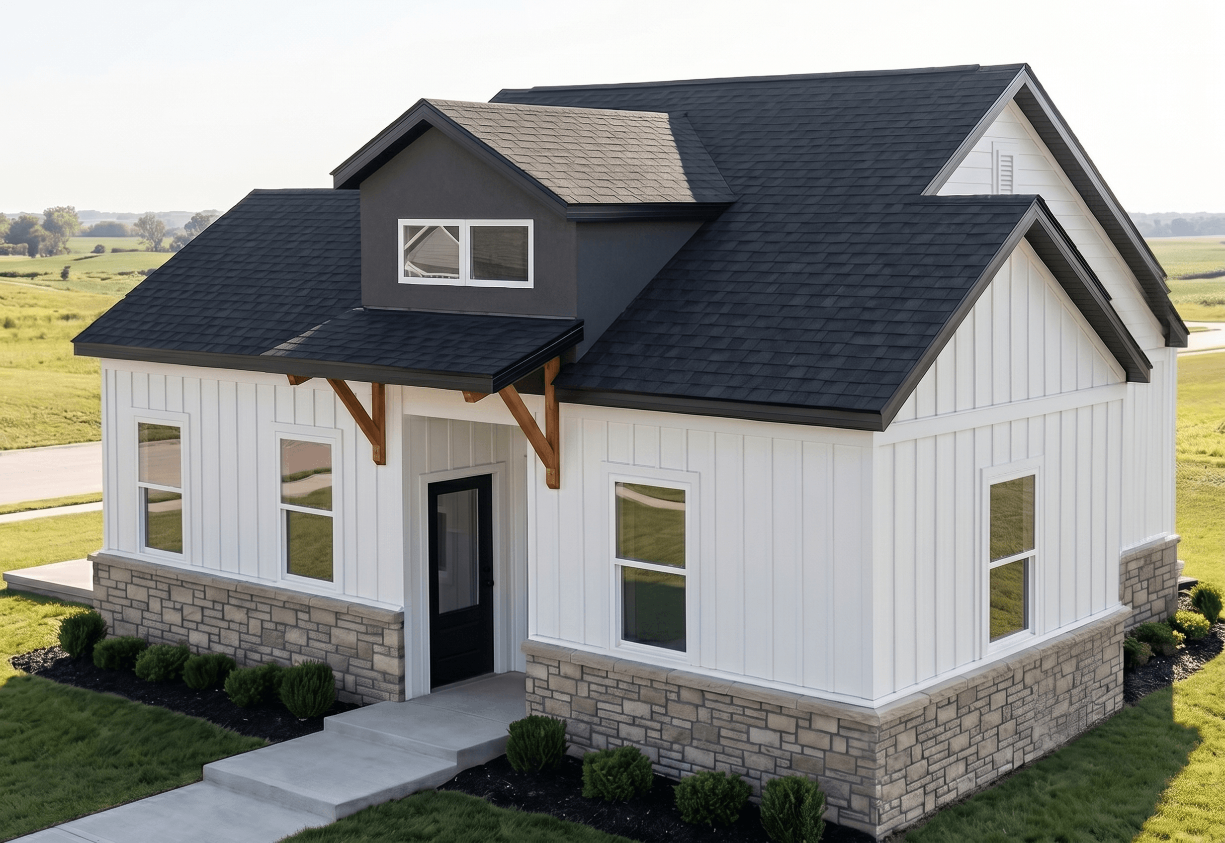 A white house with a black roof and a stone foundation.